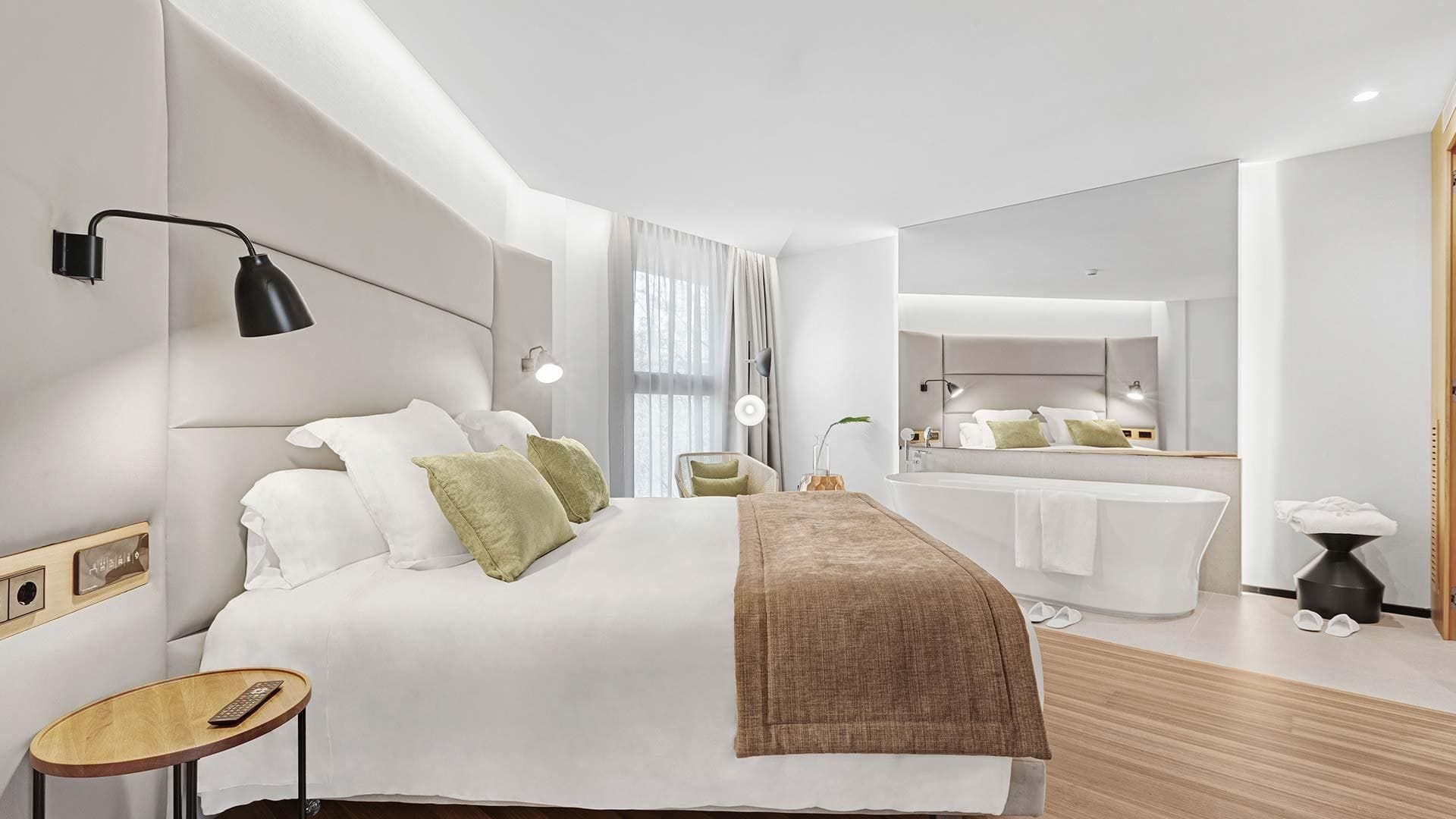 Suite Deluxe bedroom with a large bed with an upholstered headboard and a freestanding bathtub at the back