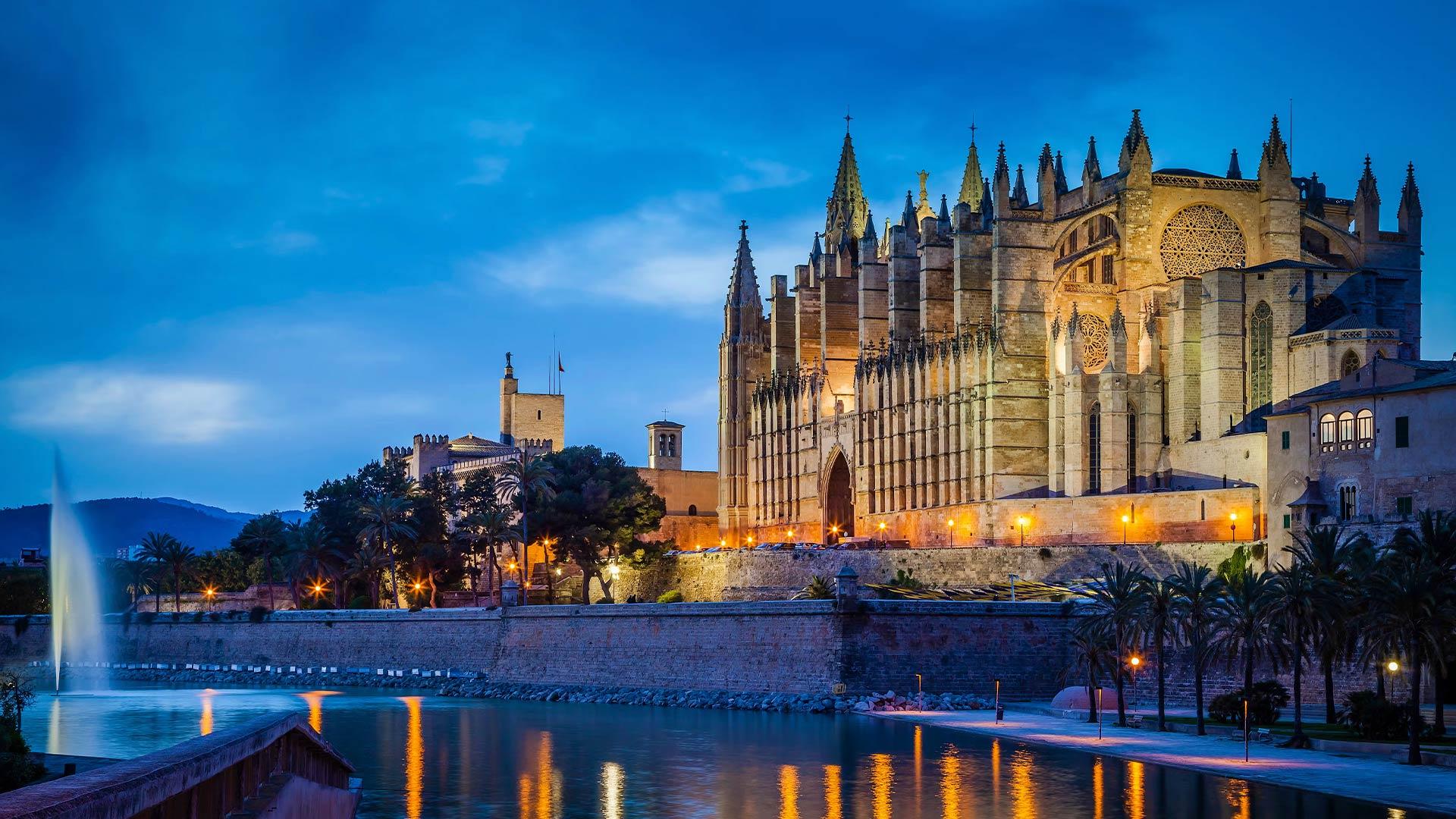 La Catedral de Palma il·luminada al vespre, amb el seu reflex a l'aigua
