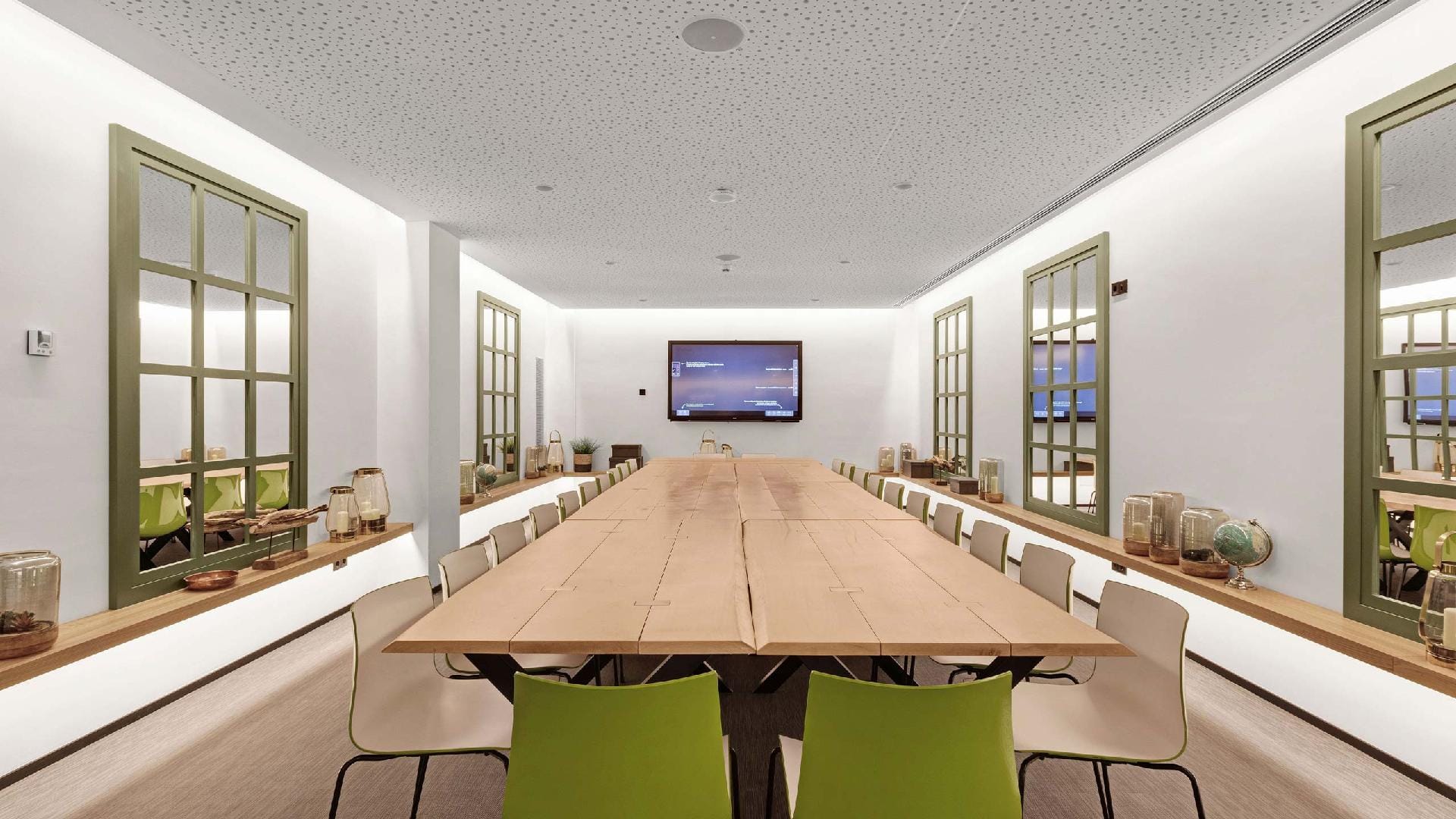 Long room with a large wooden table, chairs and a screen at the back