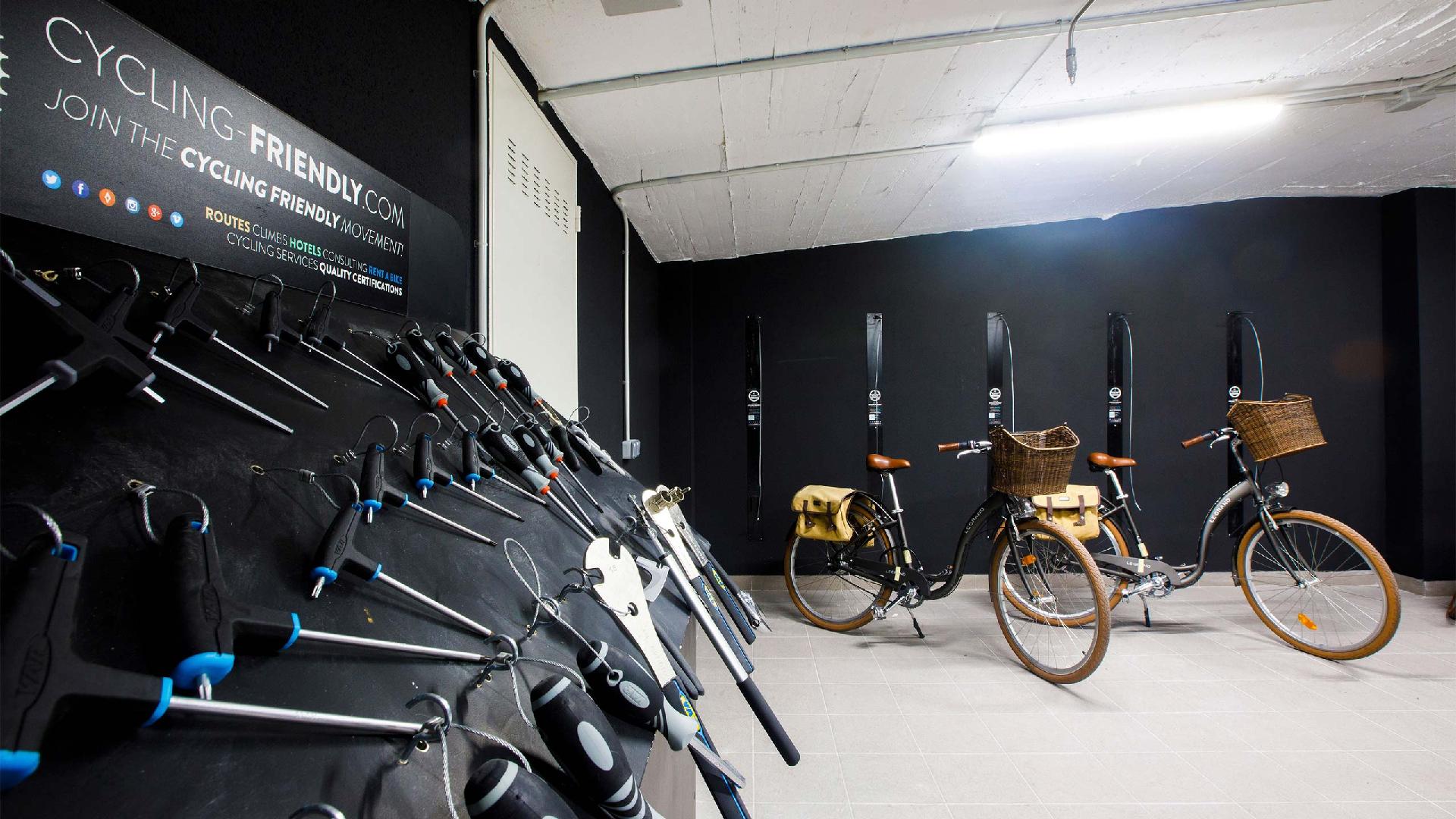Coin de la salle des vélos avec un panneau d'outils suspendus et deux vélos de balade avec panier en osier et sacoches